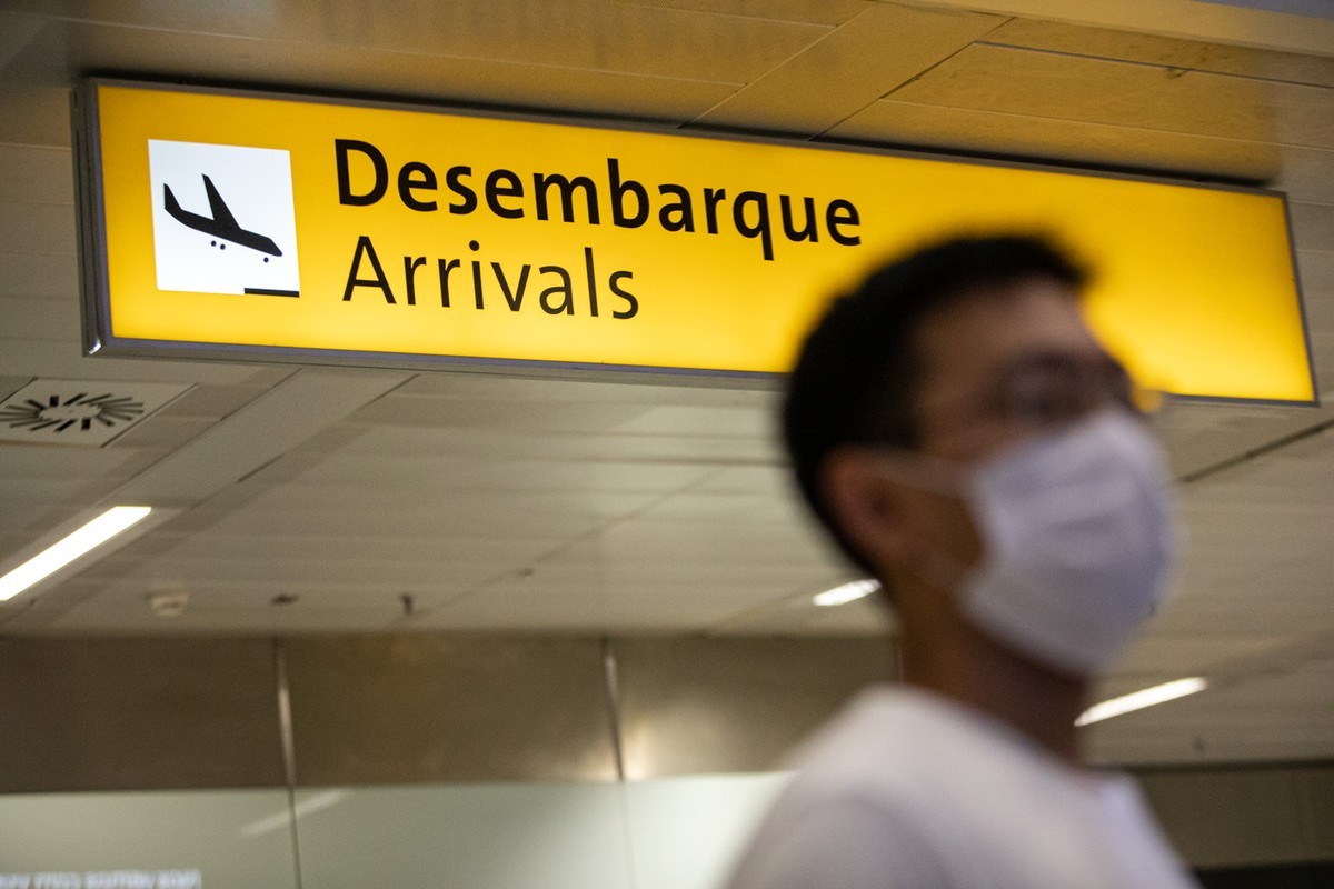 Turista na área de desembarque no aeroporto com máscara facial para evitar o coronavírus.